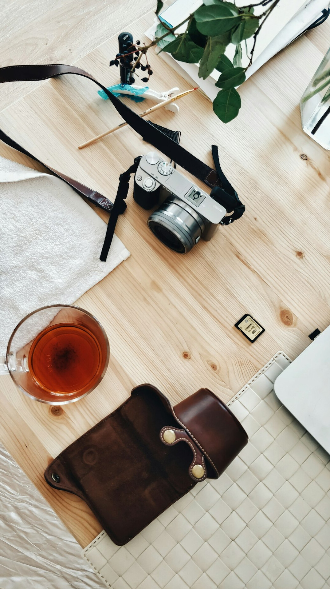 Overhead view of a desk with a vintage camera, contact sheets and a cup of tea