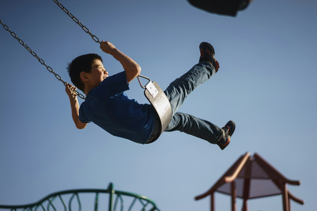 Caucasian-Canadian child laughing on a swing at a neighborhood playground